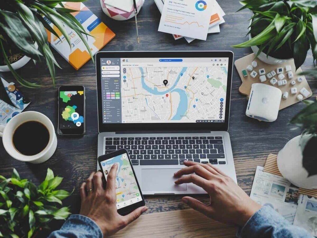 Digital marketing setup with laptop, smartphone, and maps.